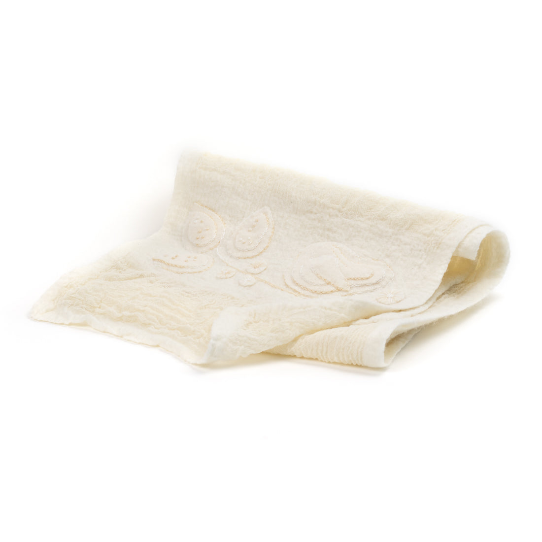 Folded Merino wool shawl shows subtle floral details on a plain surface.