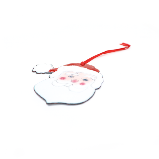 Santa Ornament featuring a jolly face with rosy cheeks, white beard, and red hat, hanging from a ribbon.
