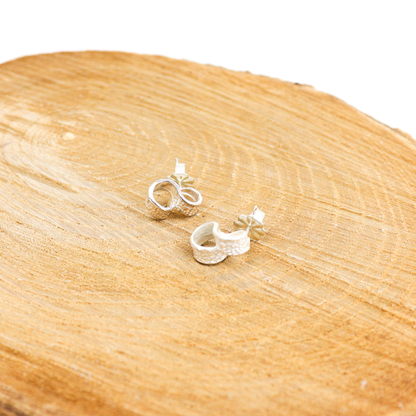 New York Button Studs displayed on a wooden surface, showing textured silver loop design.
