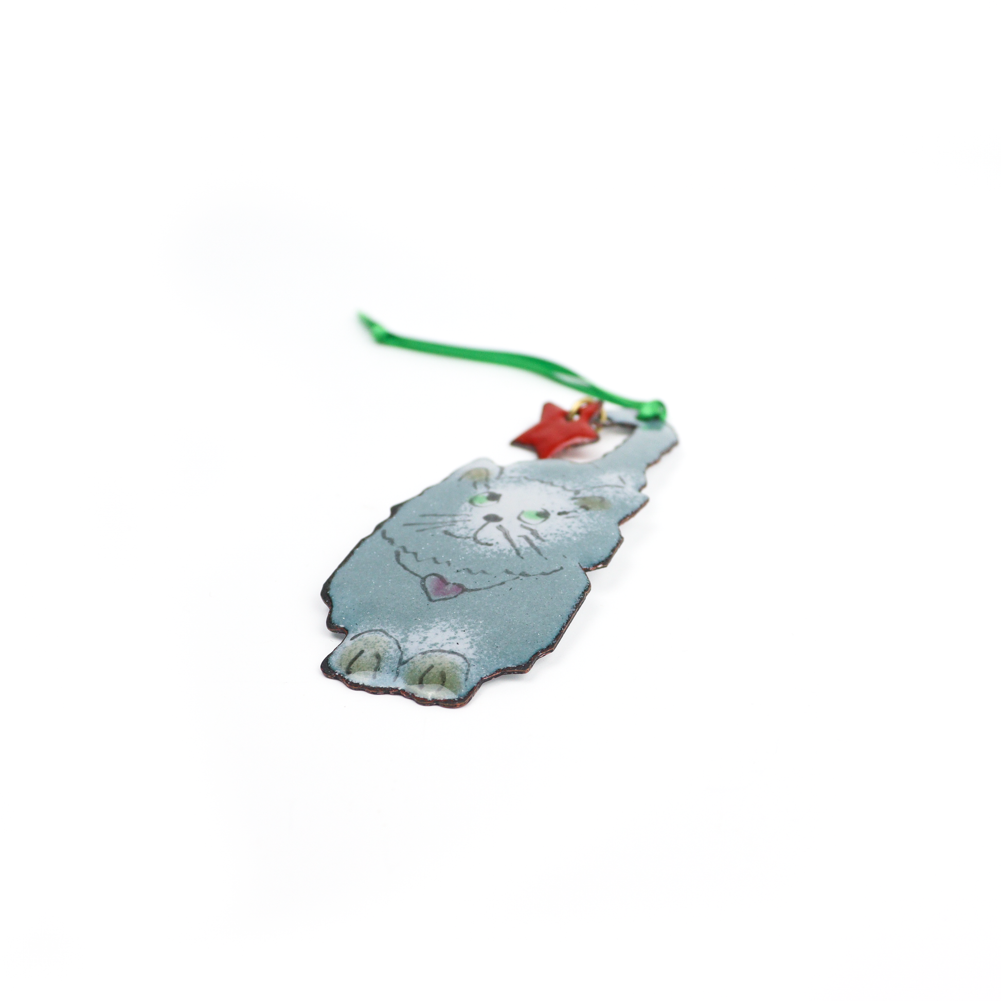 Gray and white cat Christmas ornament holding a red star by its tail with a green ribbon for hanging.
