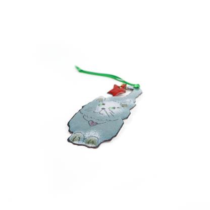 Gray and white cat Christmas ornament holding a red star by its tail with a green ribbon for hanging.