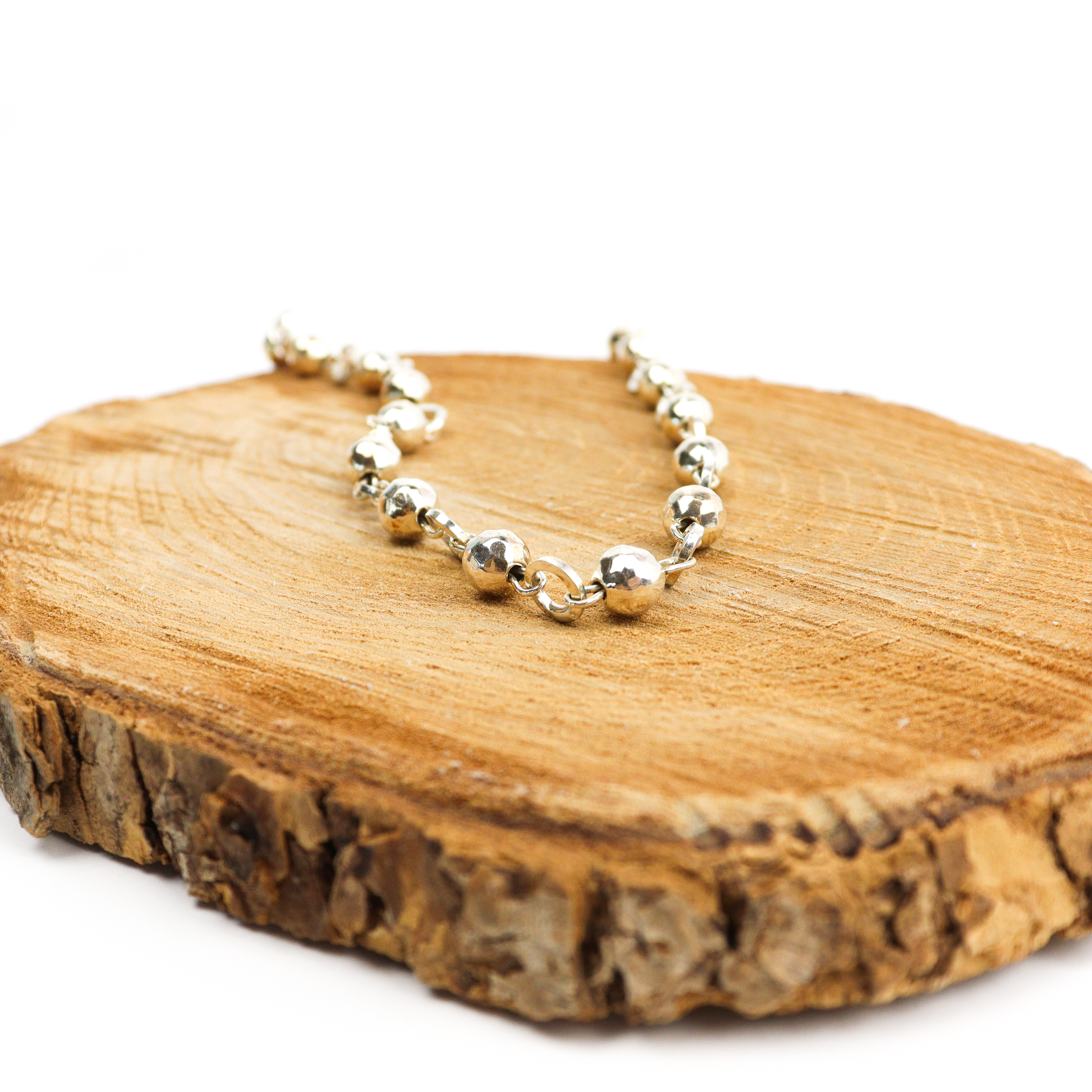 Ball & Chain Necklace displayed on a wooden surface, showcasing polished silver balls and links.