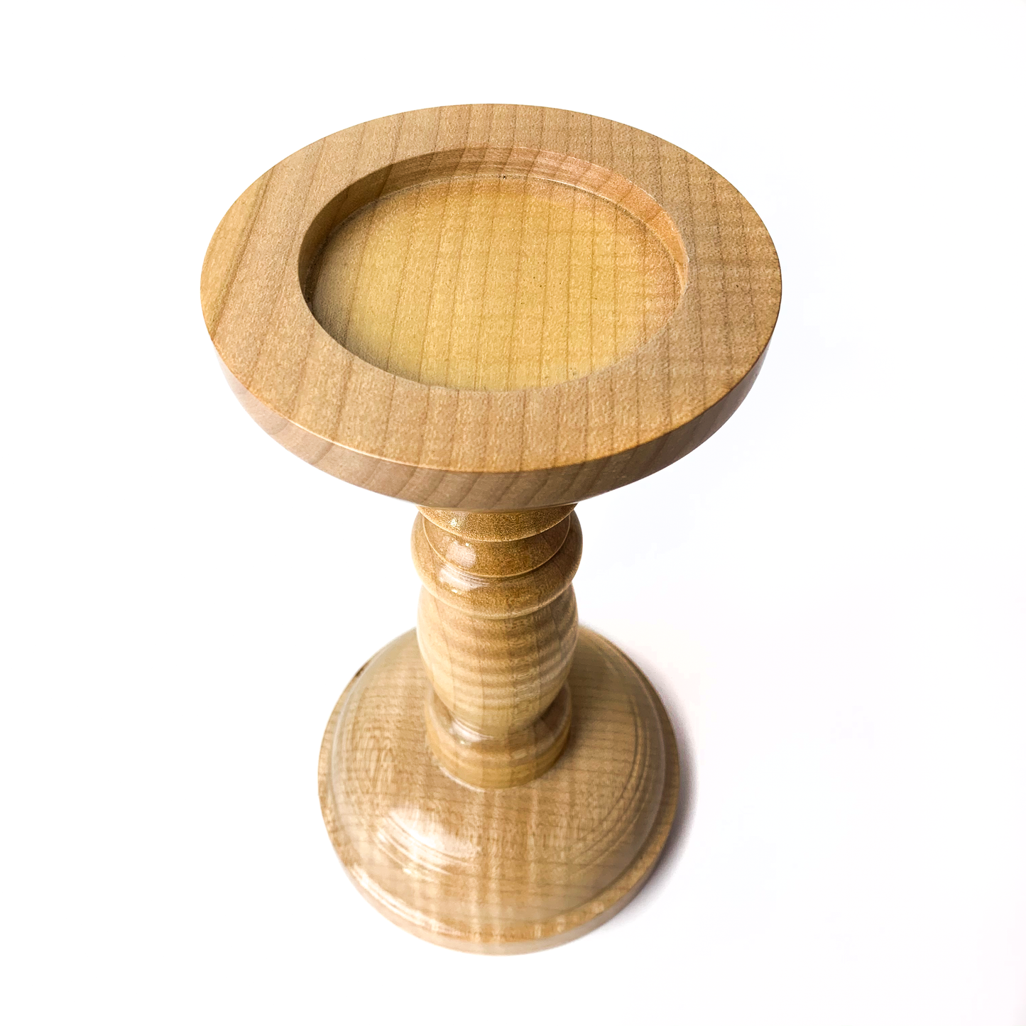 A light wooden candle holder with a circular recessed top.