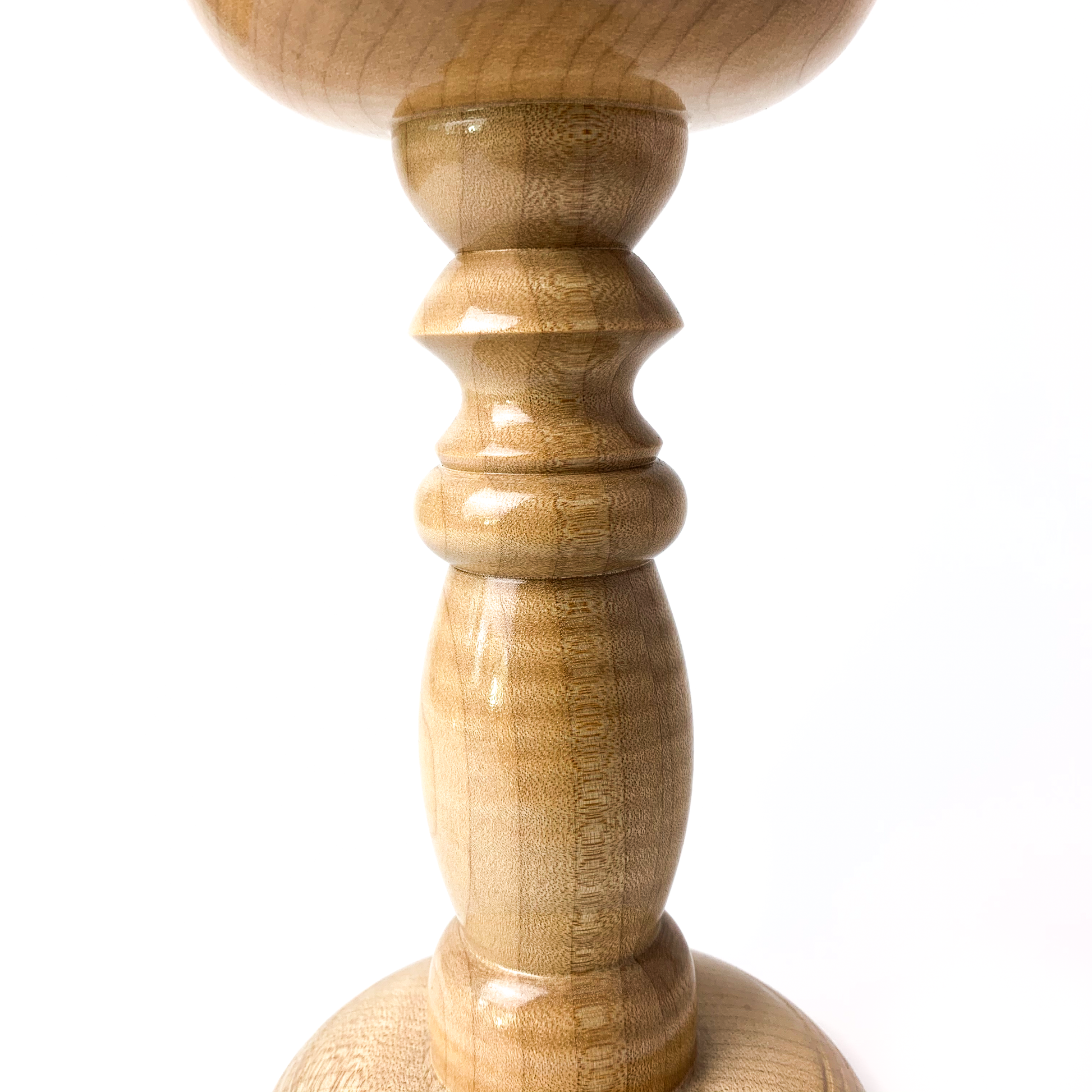 Close-up of a light wooden candle holder with a turned stem.