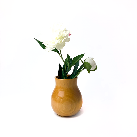A small, light brown wooden vase with two white flowers.