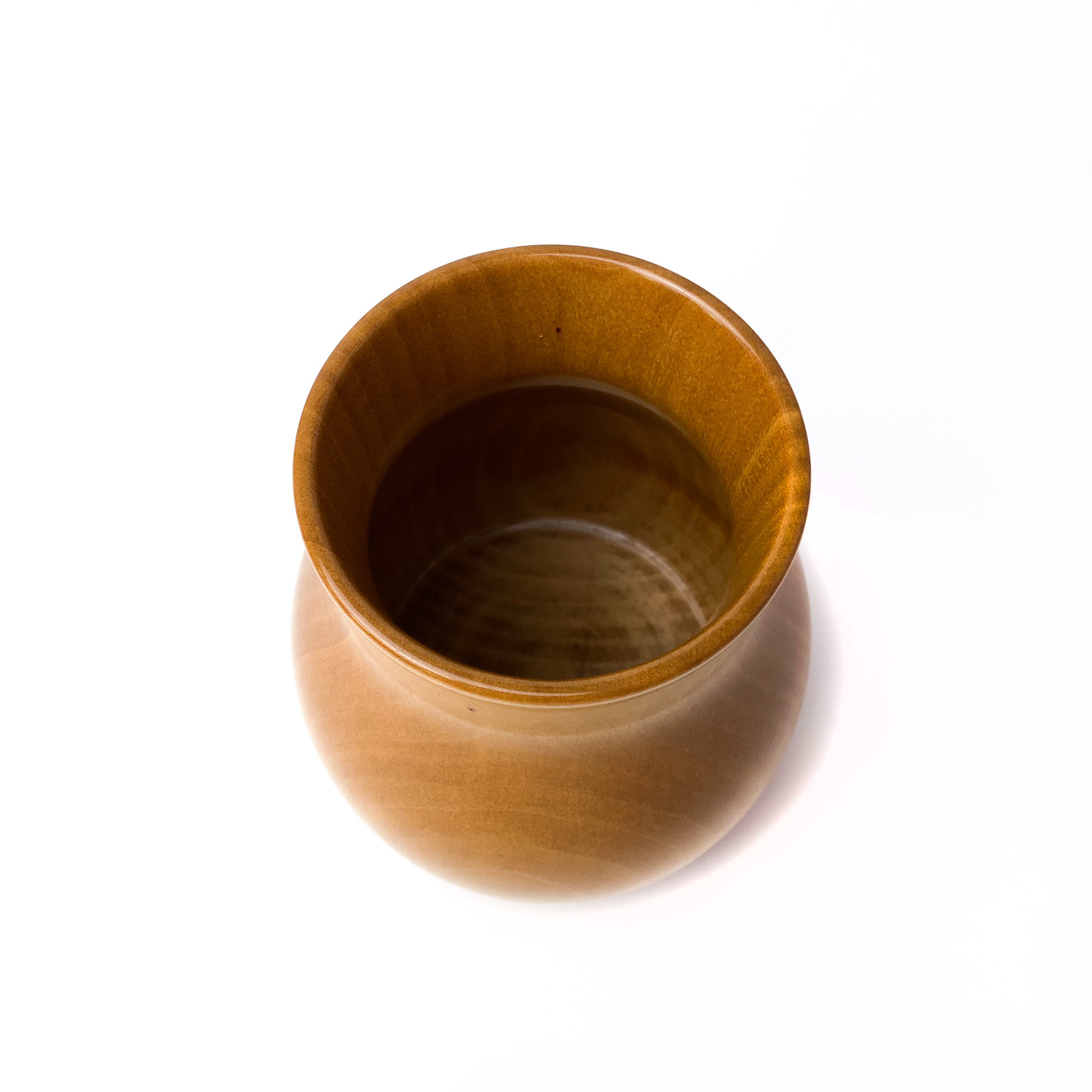A small, light brown wooden vase, top-down view.