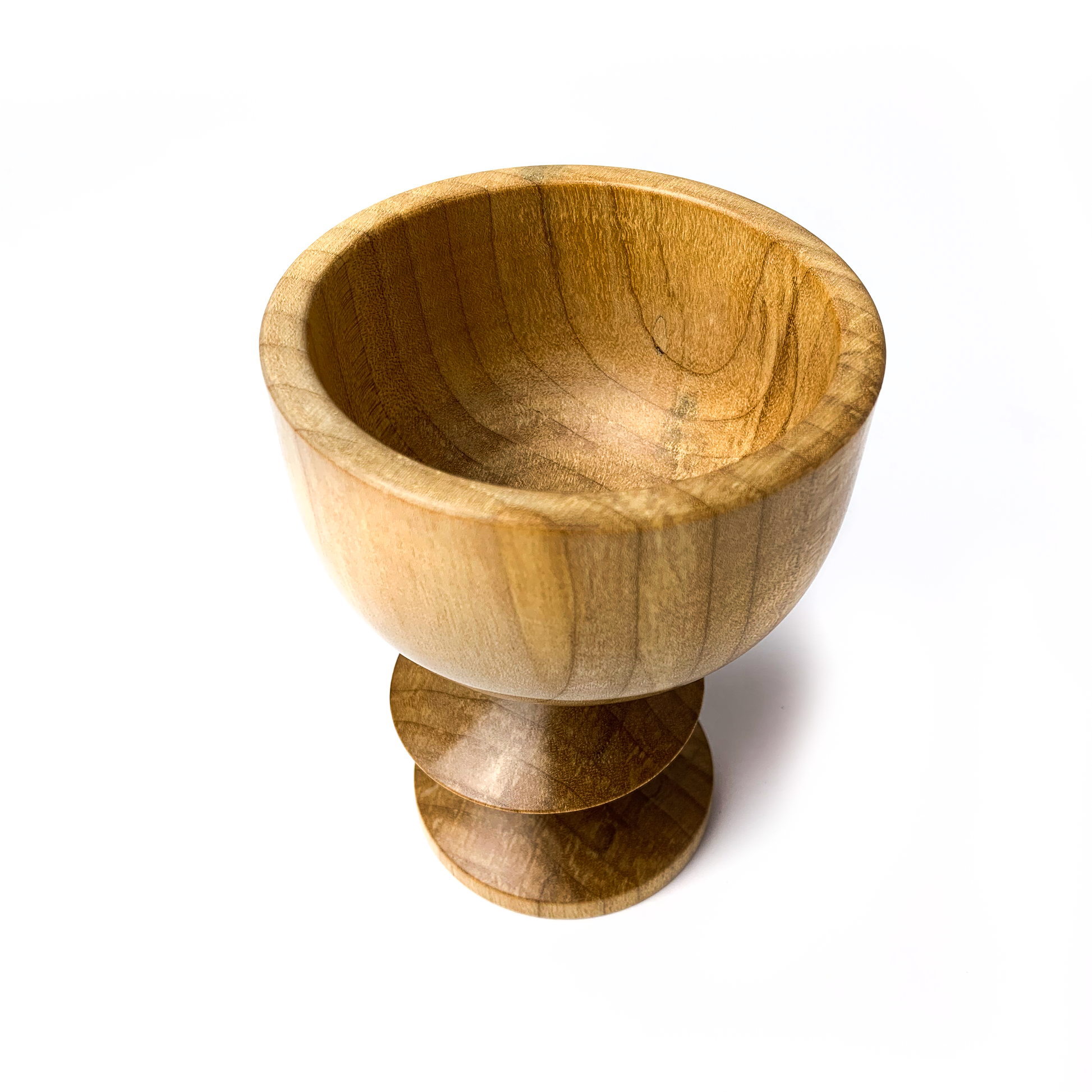 A light brown maple goblet with a rounded bowl and a twisted stem, angled view.