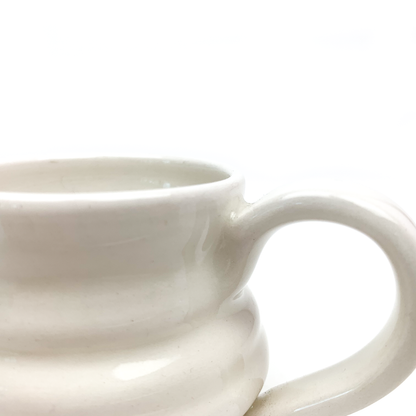 Close-up of a ceramic mug showing its curved handle and the textured, ridged surface of the body.