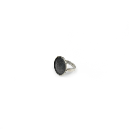 Silver ring with a large, round, dark textured face featuring a radiating design. Inscriptions "925" and "DMT" are visible on the band.