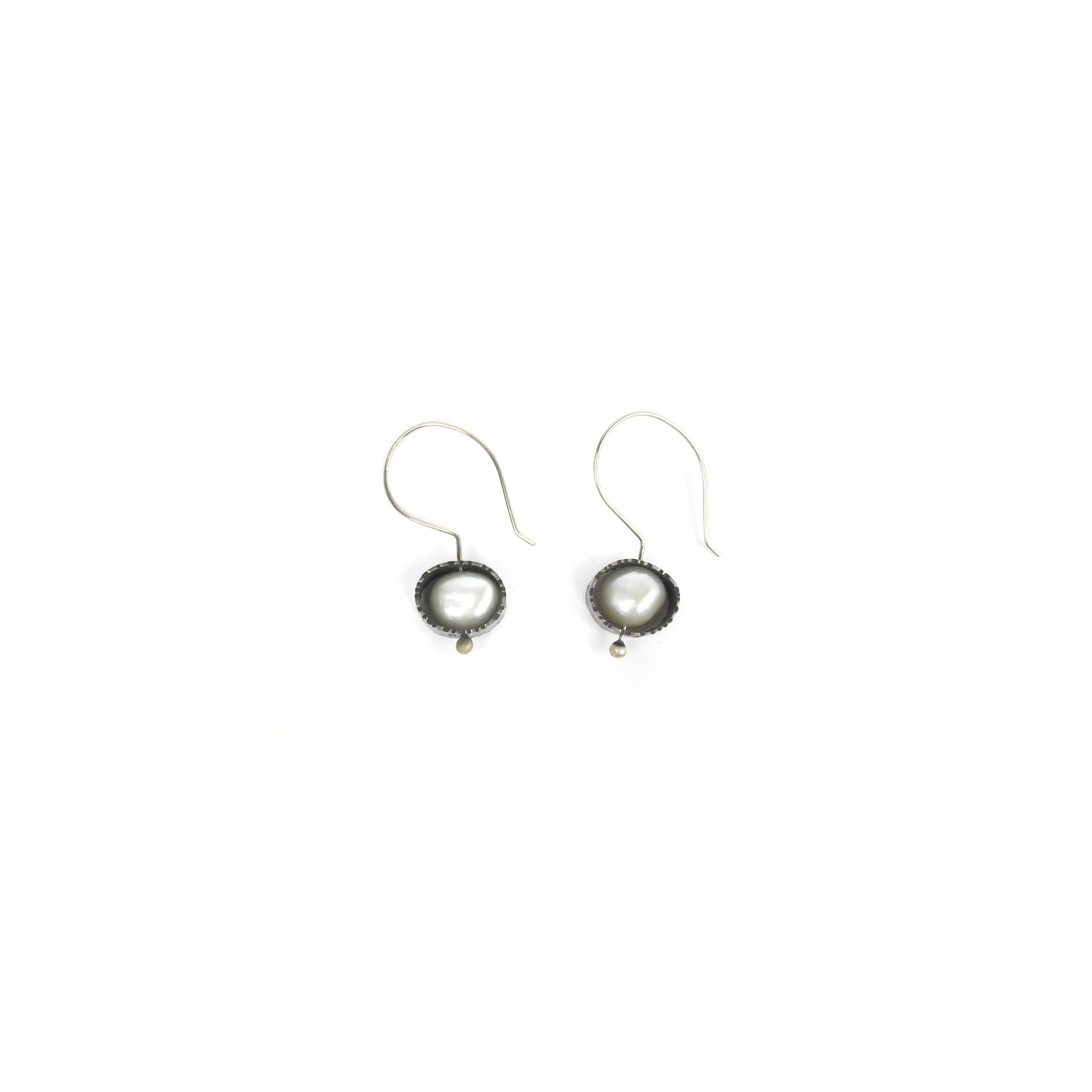 Two silver earrings feature baroque pearls set in textured, circular bezels and hang from silver ear wires.