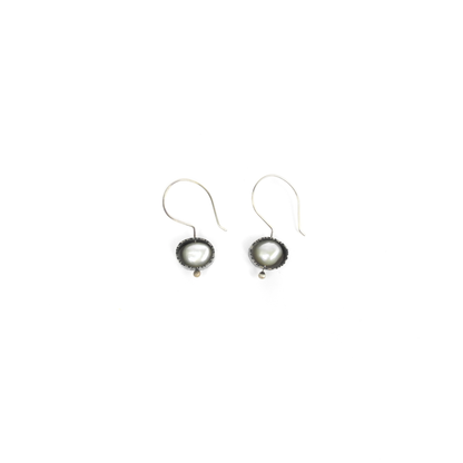 Two silver earrings feature baroque pearls set in textured, circular bezels and hang from silver ear wires.