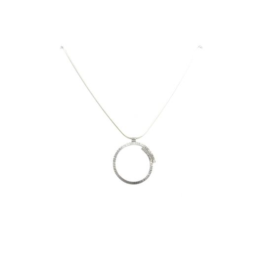 A metallic pendant with a textured circular design hangs from a delicate chain.