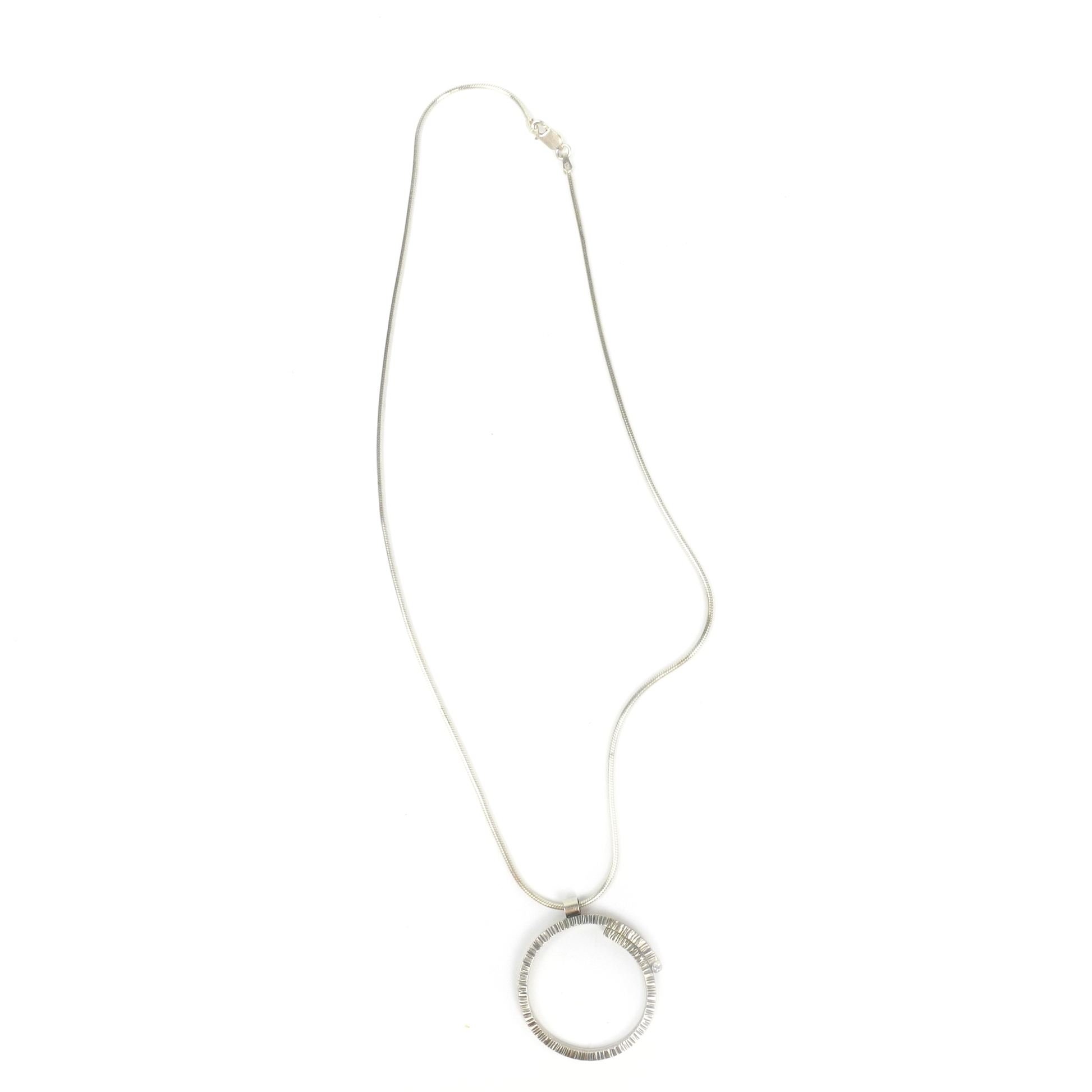 A metallic pendant with a textured circular design hangs from a thin chain.