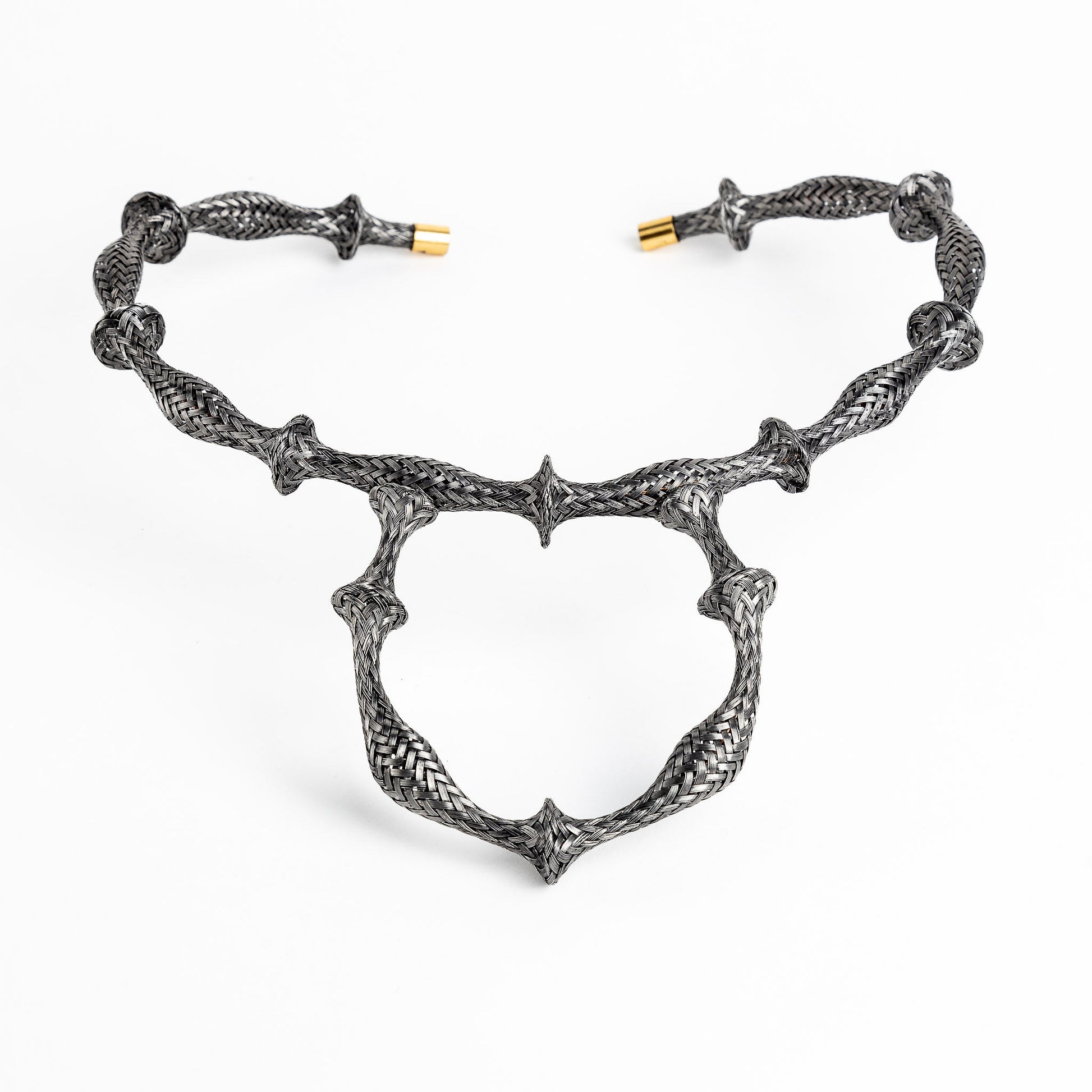 Braided stainless steel cuff bracelet with gold end caps, curved in a heart shape, on white.