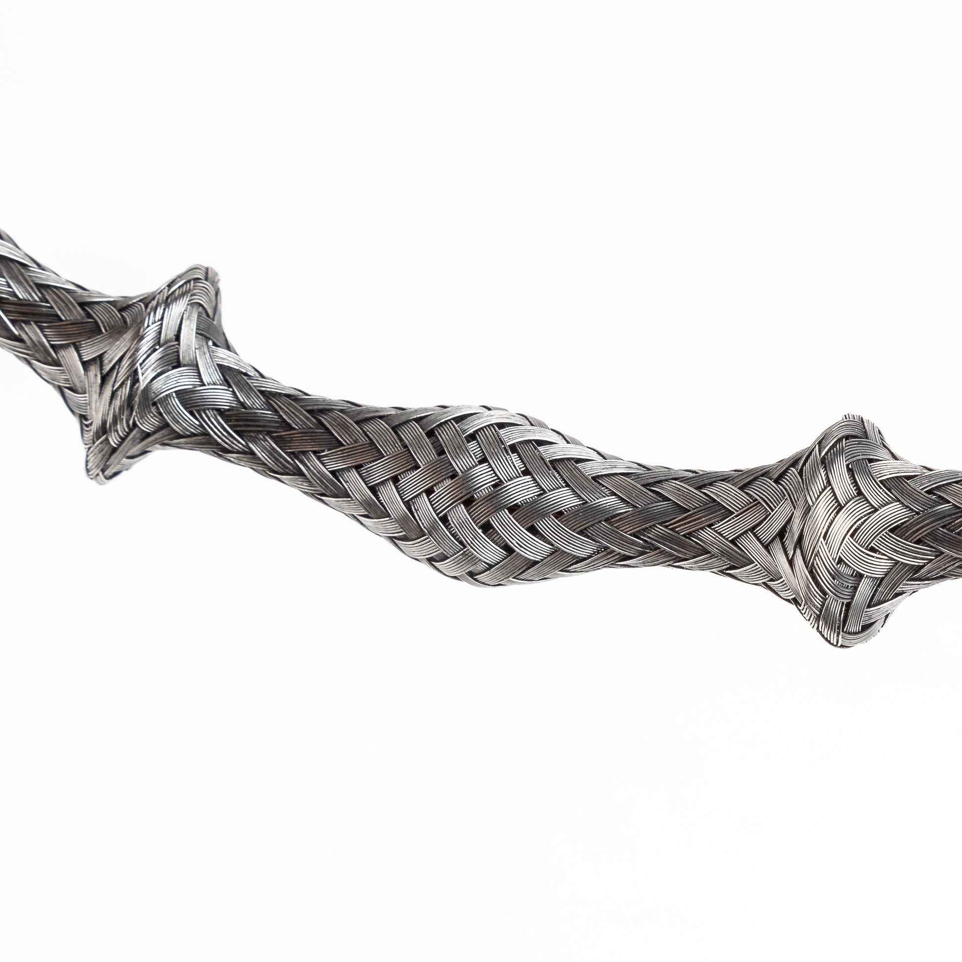 Close-up of a braided stainless steel cuff bracelet section, slightly curved, on a white background.