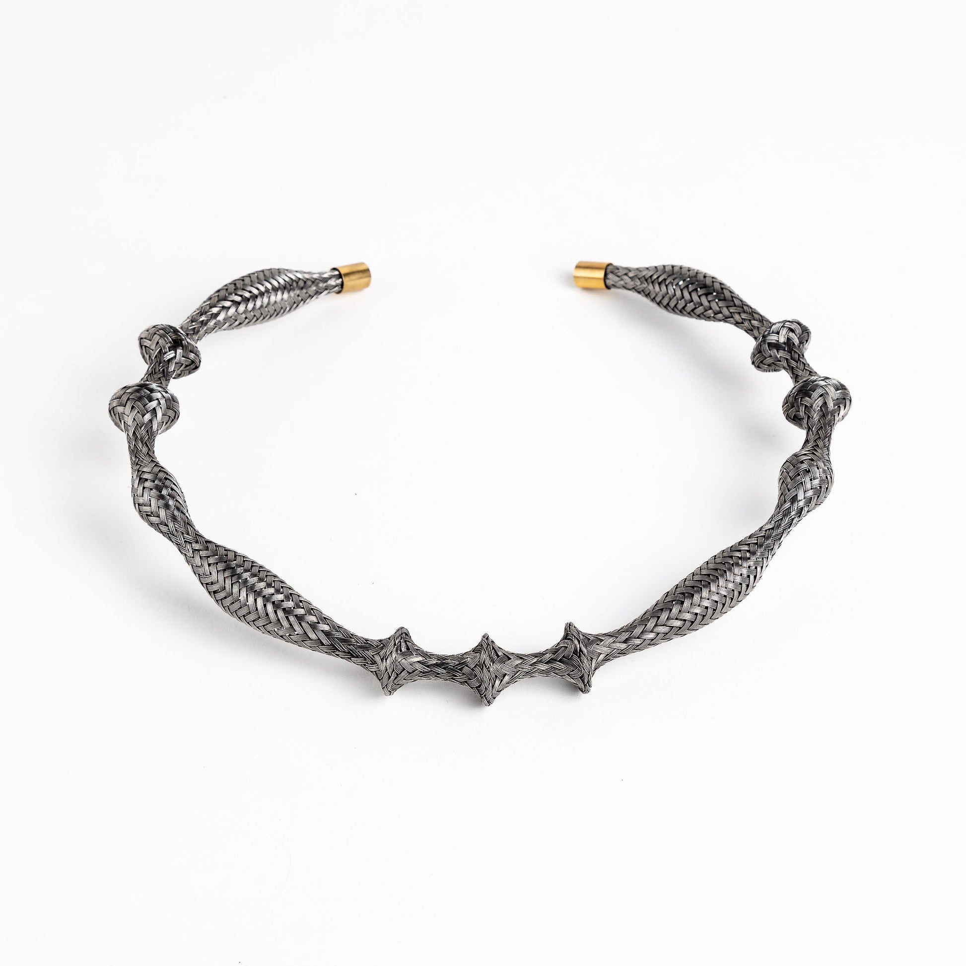 Curved stainless steel braided necklace with gold end caps on a white background, angled view.