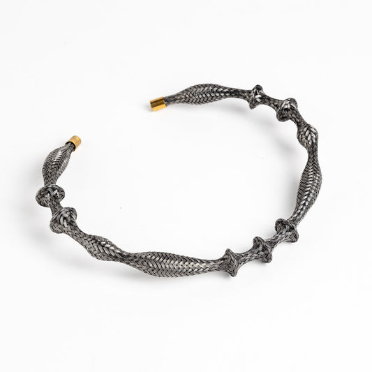 Curved stainless steel braided necklace with gold end caps on a white background, angled view.