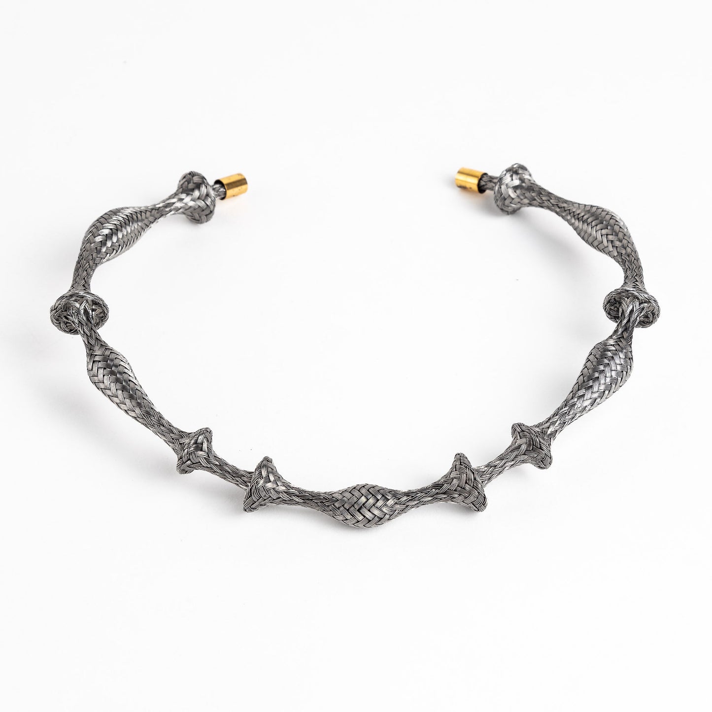 Braided stainless steel cuff bracelet with gold end caps, curved, on a white background.