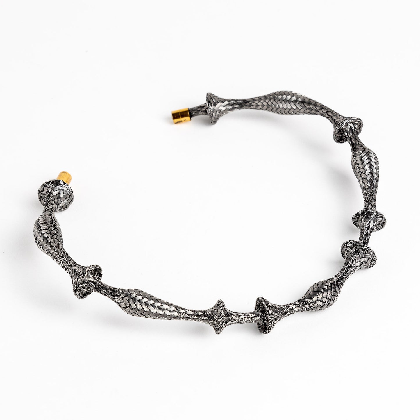 Braided stainless steel cuff bracelet with gold end caps, curved, on a white background.