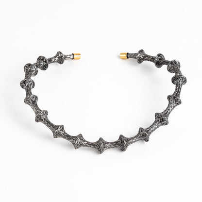 Braided stainless steel cuff bracelet with gold end caps, curved, on a white background.
