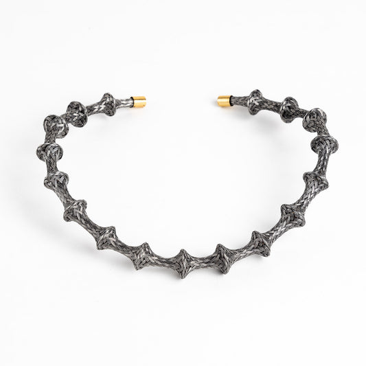 Braided stainless steel cuff bracelet with gold end caps, curved, on a white background.