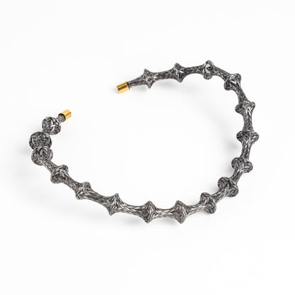 Braided stainless steel cuff bracelet with gold end caps, curved, on a white background.