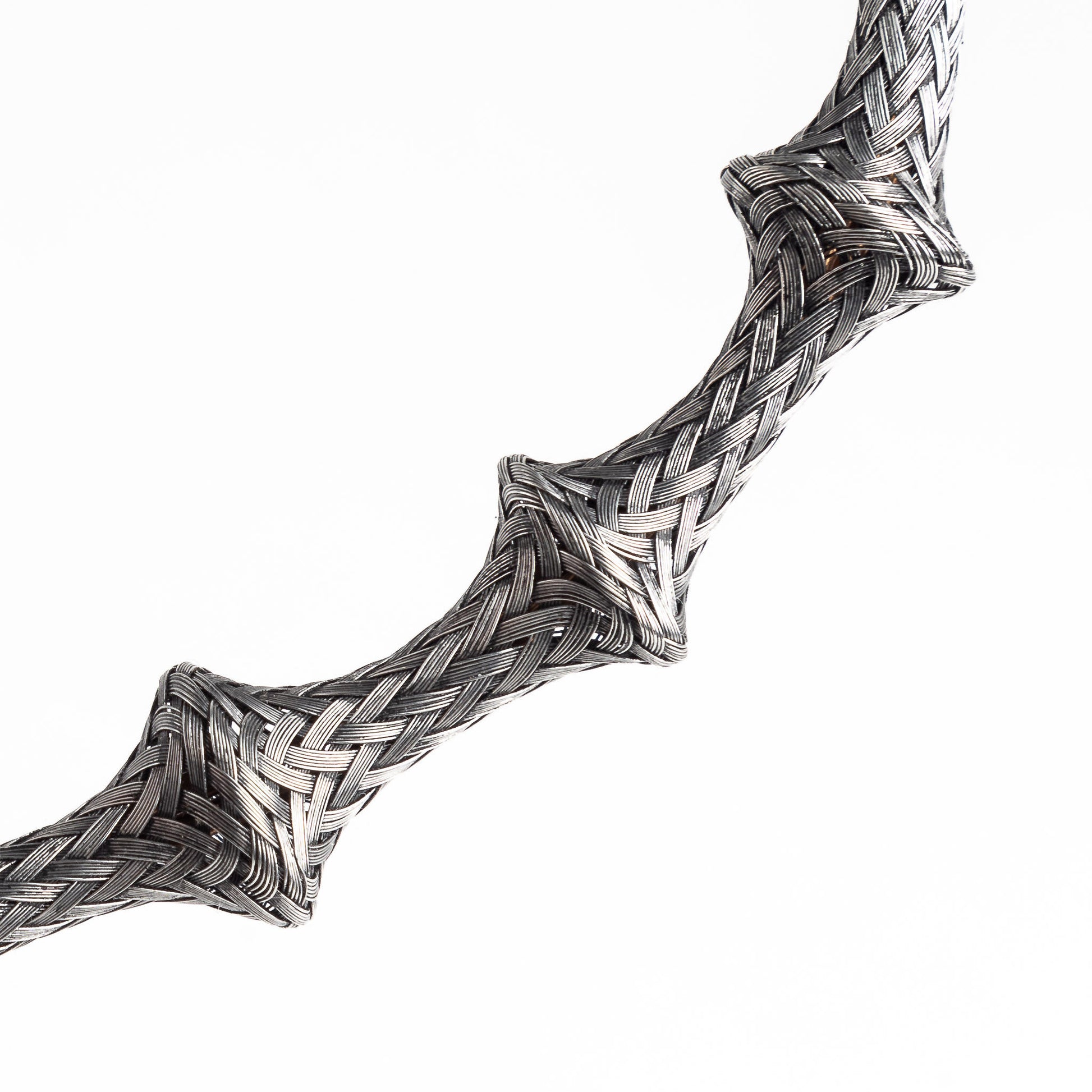 Close-up of a braided stainless steel cuff bracelet section, angled, on a white background.