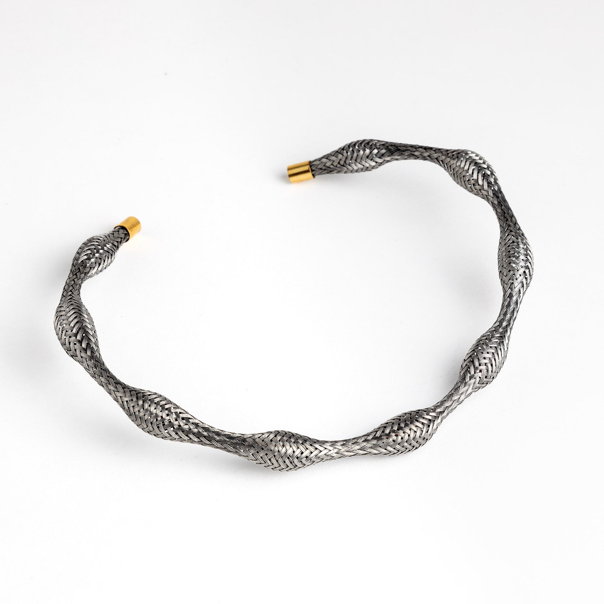 Curved stainless steel braided necklace with gold end caps, angled.