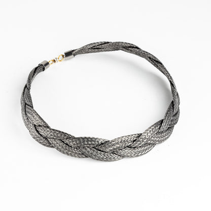 Braided stainless steel necklace with gold clasp, slightly angled, on a white background.