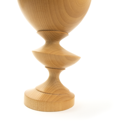 A light brown wooden goblet with a rounded bowl and a twisted stem, close-up angled view.